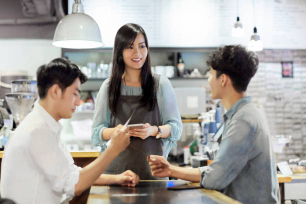 istock Young waitress taking order from customers in cafe 1169179135