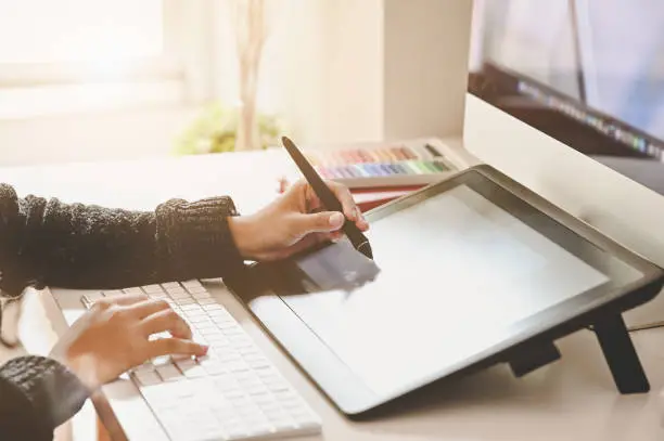 Photo of Cropped shot designer woman's hands using pen and digital tablet with computer.