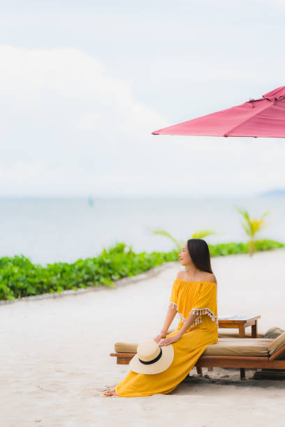 istock Woman Sitting On Beach Against Sky 1169184018