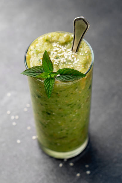 Vegetable green smoothie in a glass on a dark background