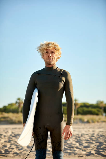 istock Confident man carrying surfboard at beach 1169188389