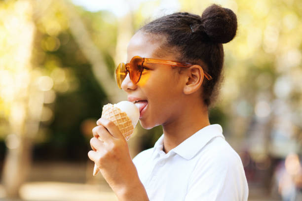 アイスクリームを食べる明るいサングラスでかわいい女の子 - nature curly hair smiling human face ストックフォトと画像