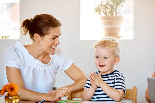 istock Happy mother looking at son clapping at table 1169191849