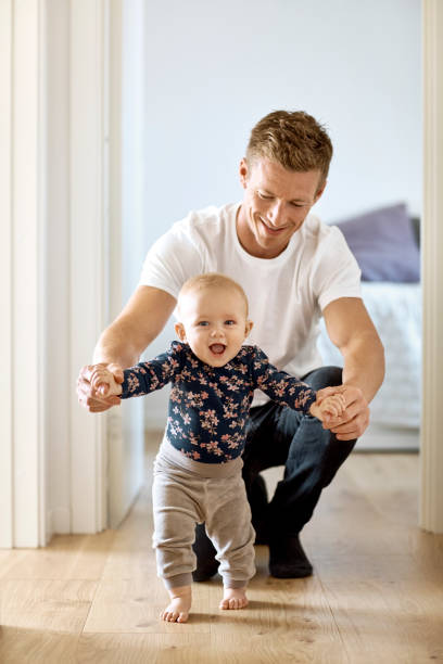 istock Happy father teaching son to walk at home 1169191925