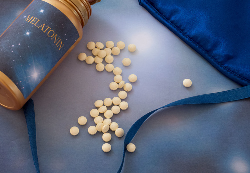 Suplementos de melatonina y máscara de sueño en el fondo azul photo