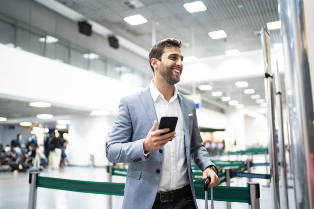 geschäftsmann steigt mit handy am flughafen ein - heathrow airport stock-fotos und bilder