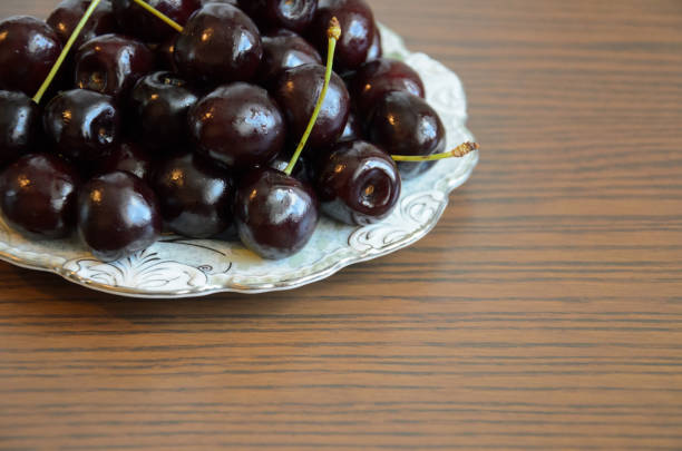 istock Wet chilled cherries with peduncles on saucer on table 1169198366