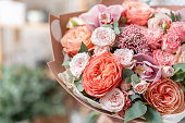 beautiful fresh cut bouquet of mixed flowers in woman hand. the work of the florist at a flower shop. Delicate Pastel tones color