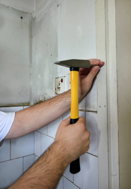 istock Construction worker and handyman working on renovation work. Builder with yellow hammer strikes and nails a nail into wooden wall of kitchen door at construction site. Apartment renovation concept. 1169206207