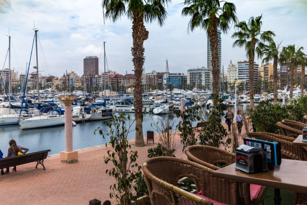 View from a cafe with rattan furniture on a port with yachts and a waterfront ALICANTE, SPAIN - APRIL 26, 2018: View from a cafe with rattan furniture on a port with yachts and a waterfront round the world travel stock pictures, royalty-free photos & images