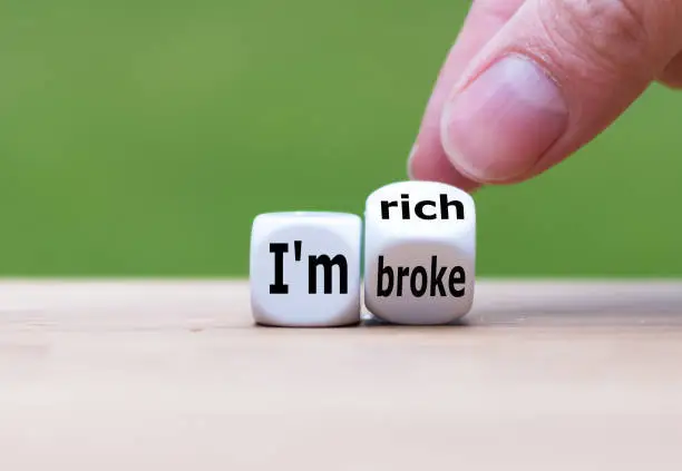 Hand turns a dice and changes the expression "I'm broke" to "I'm rich", or vice versa.