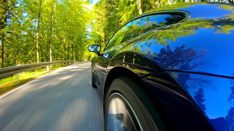 Driving fast with a sports car on a winding country road surrounded by lush foliage