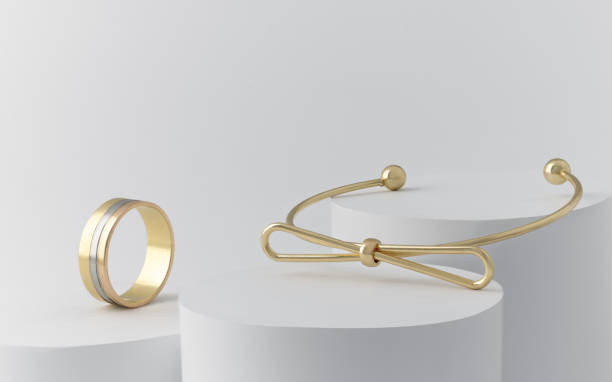 Golden bow shape Bracelet and triple ring on white cylinders with copy space