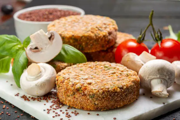 Tasty vegetarian burgers made from healthy quinoa, basil, tomatoes and champignon mushrooms close up
