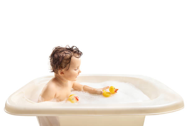 Baby having a bath and playing with duck toys isolated on white background