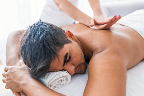 Man receiving back massage from masseur Portrait Of Man Receiving Massage Treatment From Female Hand. Close-up of masseur's hands and a client's back. Man getting relaxing massage in spa. Man receiving back massage from masseur man massage stock pictures, royalty-free photos & images