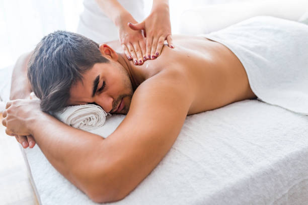 Young man is enjoying massage on spa treatment Man Enjoying Massage At Spa. Man having back massage at the health spa. Sports massage. Close-up of masseur's hands and a client's back. Man has deep tissue massage on the back. man massage stock pictures, royalty-free photos & images