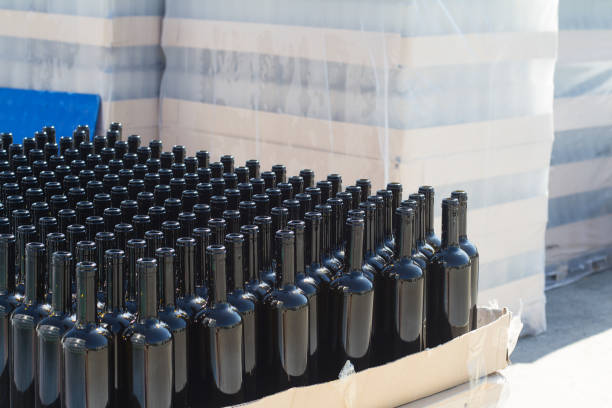 black wine bottles on pallets in outside storage area side view closeup of many black empty wine bottles arranged in rows and stacked on transport pallets in outside storage area wine shipping stock pictures, royalty-free photos & images