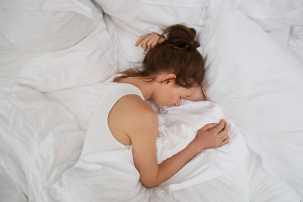 istock Young beautiful woman sleeping in bed, white sheets, top view 1169228865