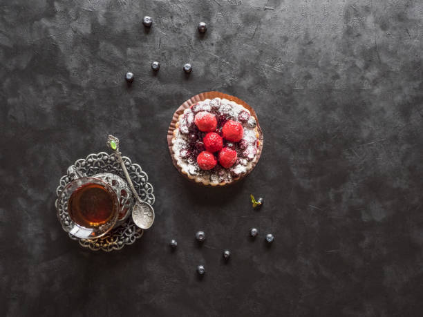 Beautiful delicious tarts, colorful pastry cakes sweets with fresh raspberries and blueberry on black background