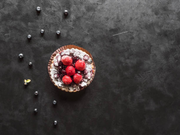 Beautiful delicious tarts, colorful pastry cakes sweets with fresh raspberries and blueberry on black background