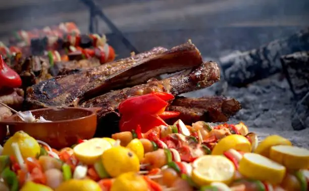 A large piece of meat and vegetable skewers on the grill at a typical argentinian asado (barbecue)