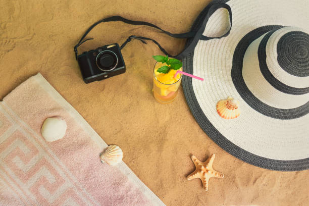 концепция летнего пляжного отдыха. фотокамера, шляпа, летний напиток, полотенце, морская звезда и ракушки на песчаном пляже. селективный фо� - shell starfish orange sea стоковые фото и изображения