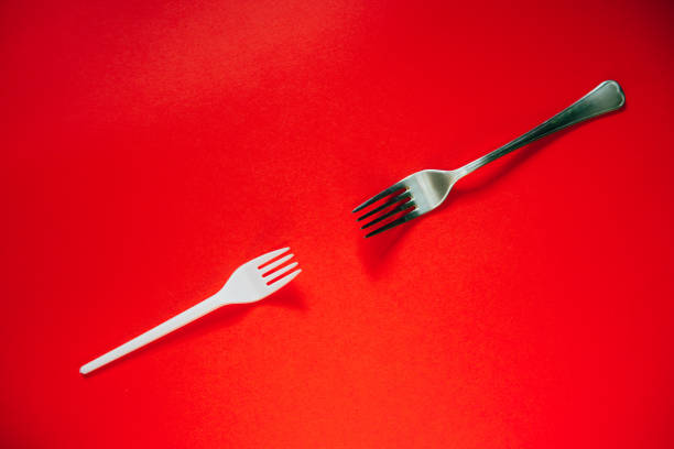 istock A plastic fork and a metal one on a red background. 1169232635