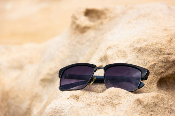 istock Dark sunglasses on yellow sandy rocks 1169235021