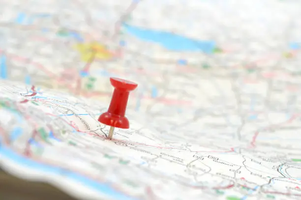 A traveler has used a red pushpin to position the mapped out destination, shallow dof with the focus on the red tack.