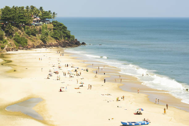 view from above, stunning aerial view of a beach with colourful beach umbrellas and people sunbathing and swimming. varkala beach is located in the south kerala at the north end border of trivandrum, india. - goa beach india green imagens e fotografias de stock