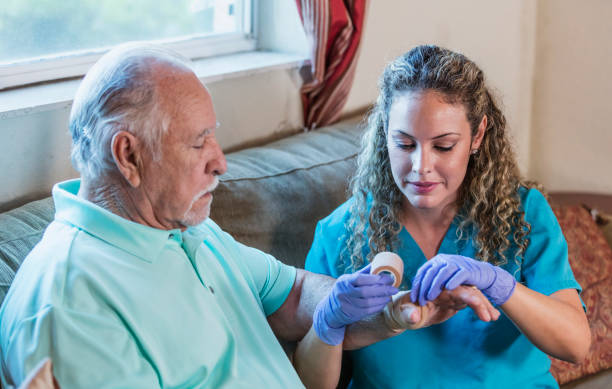 opiekun domu z starszym człowiekiem bandażującym rękę - healthcare and medicine pain candid senior adult zdjęcia i obrazy z banku zdjęć