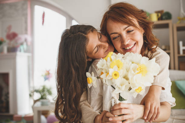 daughter giving flowers to her mother at home - mother gift imagens e fotografias de stock