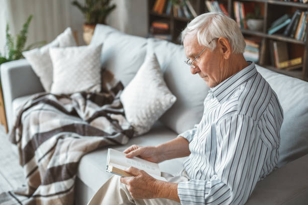 istock Senior man at home retirement concept sitting reading book side view 1169246849