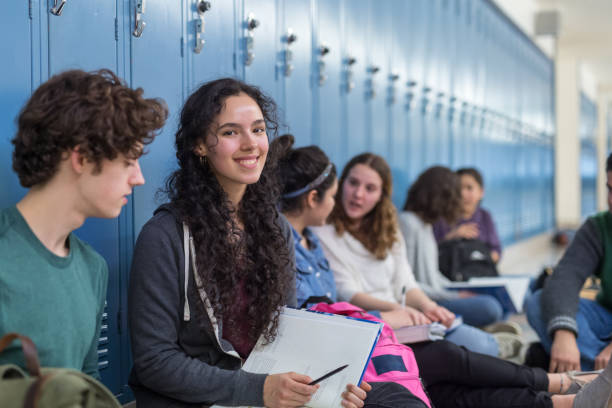 istock Multiethnic high school students sit around their lockers and hang out together 1169248826