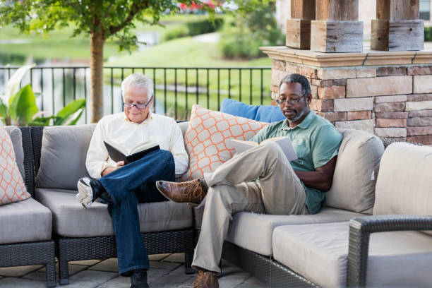 istock Retired men sitting on patio reading books 1169249057