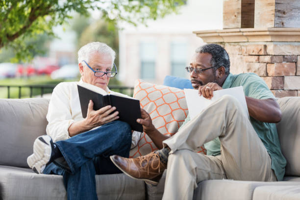 istock Retired men sitting on patio reading books, conversing 1169249249