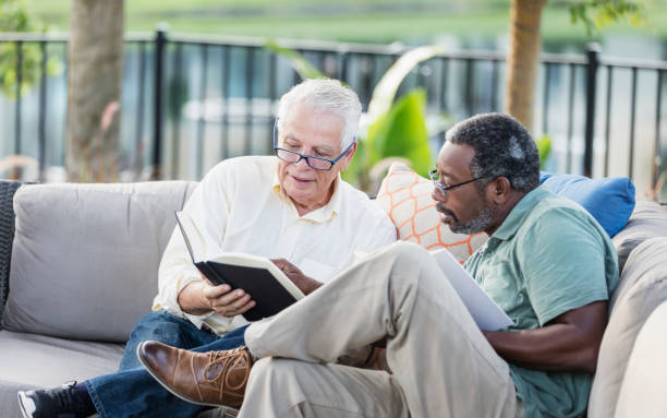 istock Retired men sitting on patio reading books, conversing 1169249346