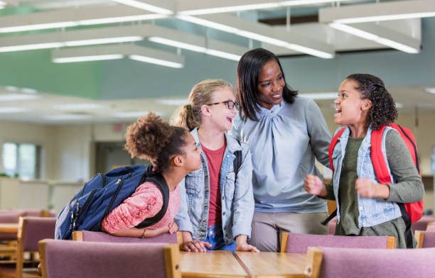 istock Elementary school girls and teacher in library 1169254802