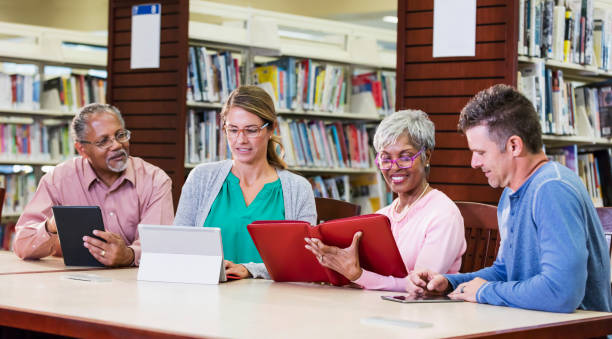 Diverse group of adult students in library, e-readers