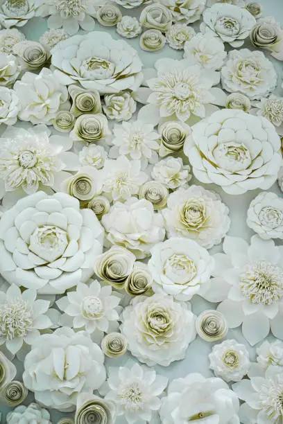 A variety of white crafted artful flowers displayed loosely organized for a backdrop.