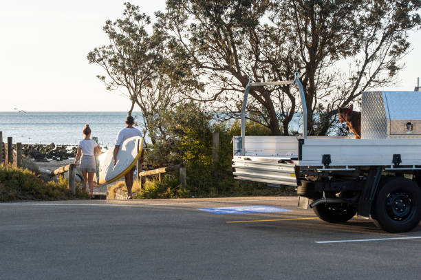 Young Australians with car at the Beach Group of young Australians at the beach in summer with the dog, Surfing Board, Workmans Ute Truck. Evening light. mornington peninsula photos stock pictures, royalty-free photos & images