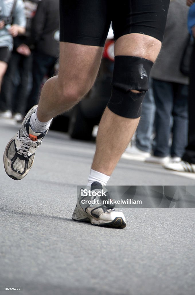 Corredor de Maratona, um joelho feridos, mas mantém a correr - Royalty-free Alfalto Foto de stock