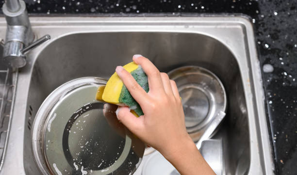 istock boy washing dishware in the kitchen sink with soapy sponge 1169269128