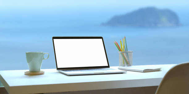 istock Modern workplace with open laptop with sea view background 1169269969
