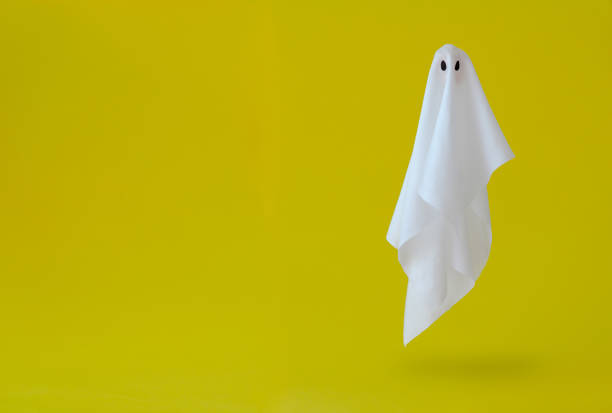 white ghost sheet costume flying in the air with yellow background. - material data sheets imagens e fotografias de stock