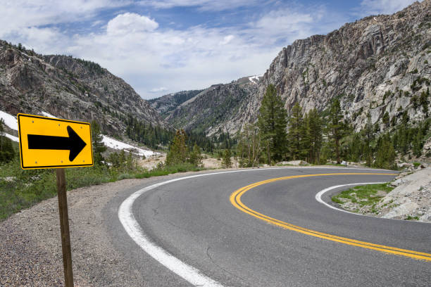 Sharp Turn Warning Arrow: A sign points the way along a winding road through the Sierra Nevada Mountains. sierra stock pictures, royalty-free photos & images