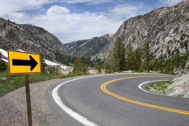 A sign points the way along a winding road through the Sierra Nevada Mountains.