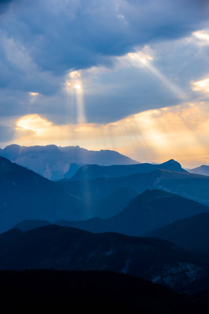 Morning landscape in blue tones in the mountains, with the sun shining through the clouds, Hautes-Alpes, France