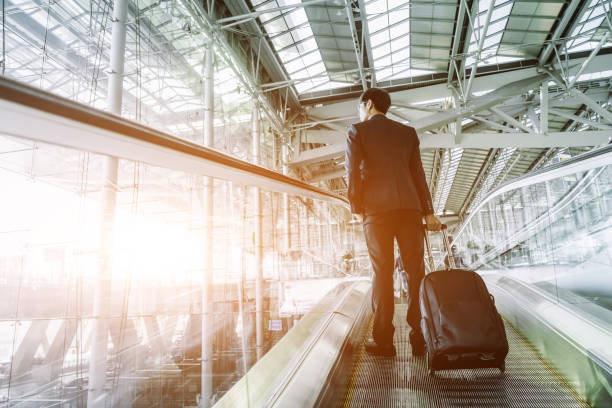 istock Businessman checking e-mail on mobile phone while walking with suitcase inside airport 1169292740